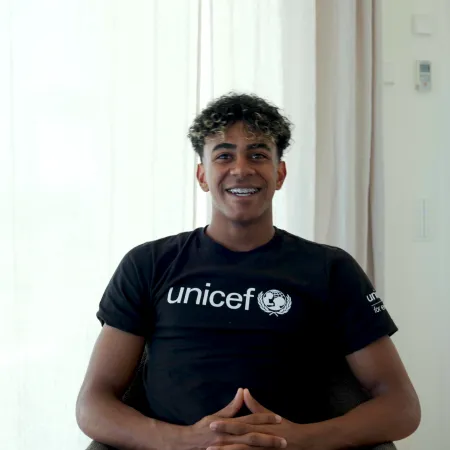 A young man in a black unicef tshirt looking at the camera and smiling. 