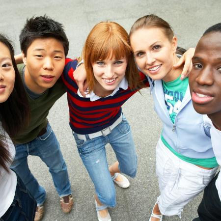 Five young people of diverse ethnic backgrounds look upwards smiling