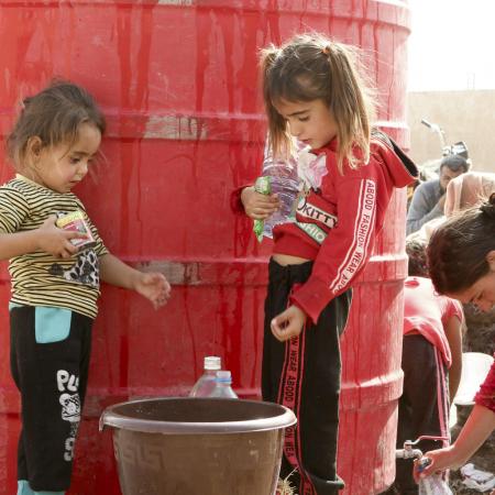 En Syrie, deux jeunes filles remplissent un seau d'eau