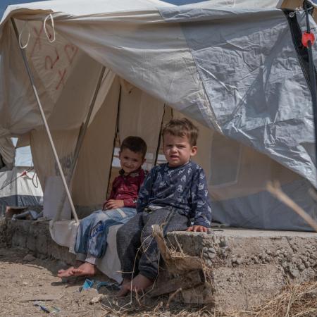 Syrian child sit outside a makeshift tent in Iraq