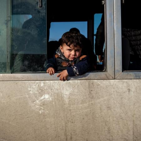 A child looks out a bus window at a temporary camp for Syrian refugees in Iraq.
