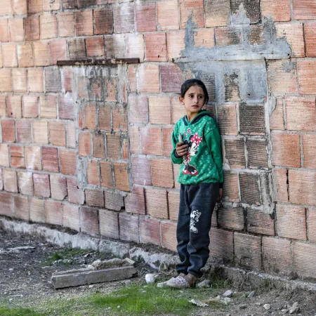 A child stands outside the ruins of a building in rural Syria.