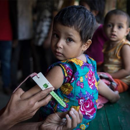 Une fillette passe un test de dépistage de la malnutrition dans une clinique soutenue par l’UNICEF dans un camp pour personnes réfugiées à Cox’s Bazar, au Bangladesh.