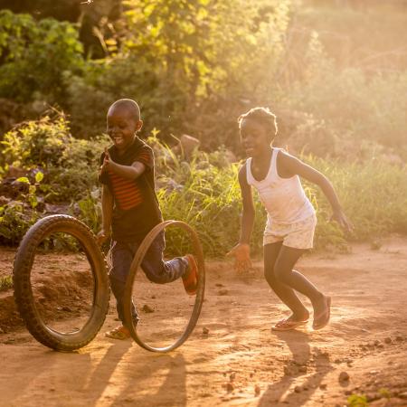 Maria and her friend play as the sun sets in Zambia. Her father Clement, receives UNICEF-supported cash transfers, which help him give her nourishment and protection