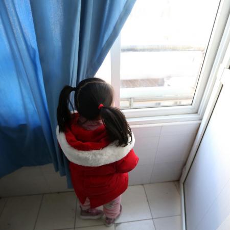 A little girl looks out a hospital window where she is being cared for while her family undergoes treatment for COVID19.