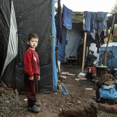 A boy stands in a makeshift camp for refugees.