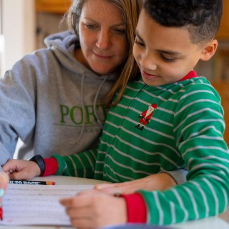 A child and mother study together at home.