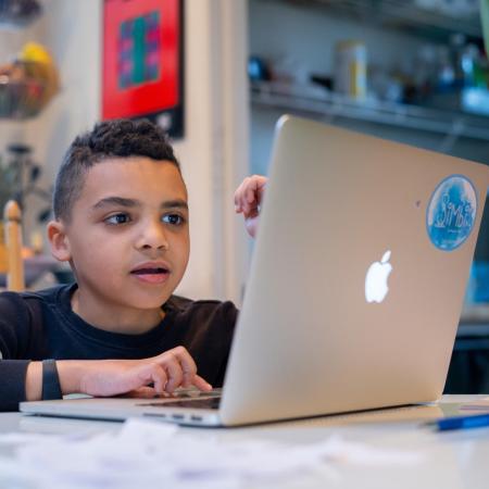 Boy doing homework on laptop at kitchen table