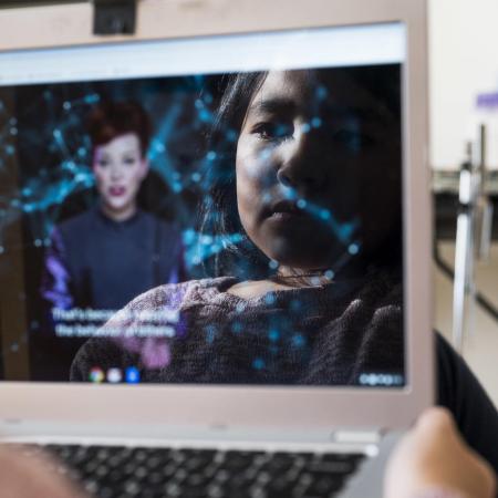 A child's face is reflected in a tablet screen.