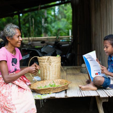 A boy reads to his grandmother in Dalli, Timor Leste.