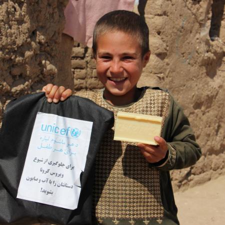 A boy shows off a bag of WASH supplies and a bar of soap.