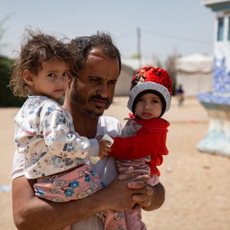 After receiving the food supplements for his 2 malnourished daughter, Moharram Al-Oshari is taking his daughters, Bulqis and Arwa back to their tent.