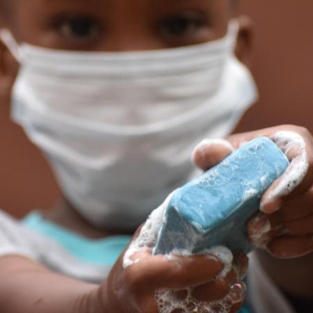 A little boy holds up a bar of soap.