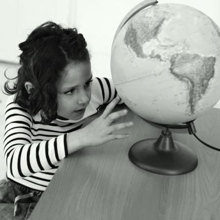 Young girl looking at a globe on a desk
