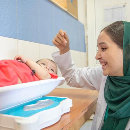 Un médecin pèse un bébé dans l’unité nutritionnelle d’un centre de santé communautaire de Herat, en Afghanistan.