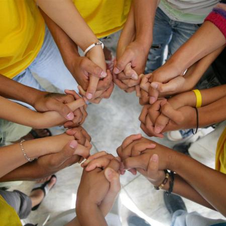 Youth leaders stand in a circle, holding hands