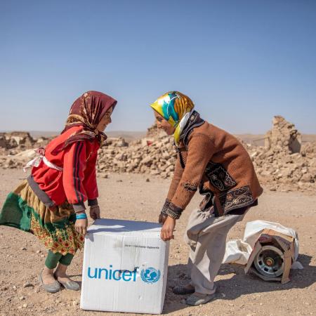 Two girls collect a family hygiene kit provided by UNICEF in Ghar Moshak District, Herat Province, western Afghanistan.