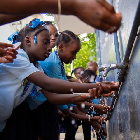 Des étudiants se lavent les mains dans le lavabo construit par l'UNICEF.