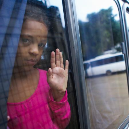 Edguimar (10), looks out of the window of the bus that will transport her to Tegucigalpa to follow the migration route to the United States, after leaving the Temporary Rest Center "Alivio del Sufrimiento" located in El Paraíso, on November 4, 2023 in Honduras.