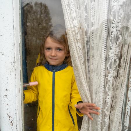 October 29, 2023,  Izium, Kharkivska oblast, Ukraine. Maria (4) is looking through the window of her house.