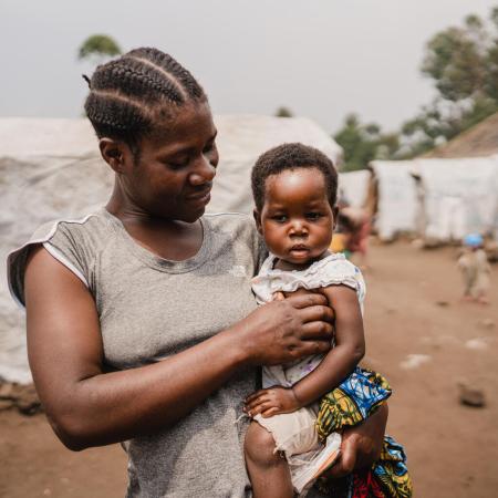 Nehema holds her daughter Queen, aged 2, after the girl's consultation at the mobile clinic set up by UNICEF and the Red Cross at the Lushagala site for displaced people, in North Kivu province, DR Congo, on 20 February 2024.