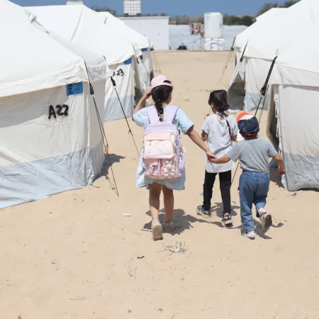 Children walk through the tents in the UK-FCDO supported camp in Rafah, southern the Gaza Strip.