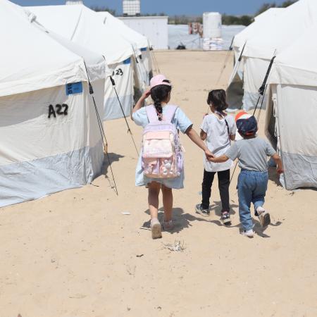 Children walk through the tents in the UK-FCDO supported camp in Rafah, southern the Gaza Strip.