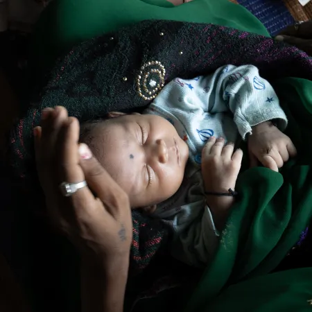 A newborn sleeps in their mother's lap in a HBPNC (Home-based postnatal care) in Balolabadi, Jhabhua, Madhya Pradesh, India. 