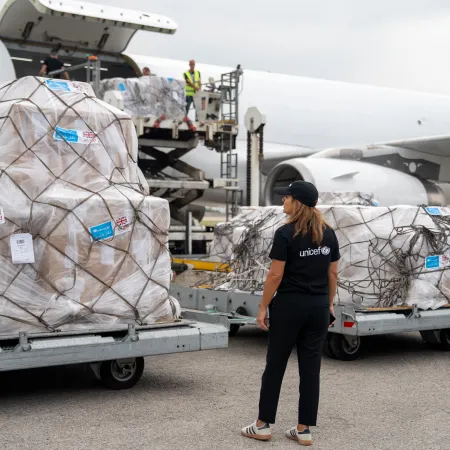 Un employé de l'UNICEF supervise le déchargement de l'aide humanitaire d'un avion-cargo.