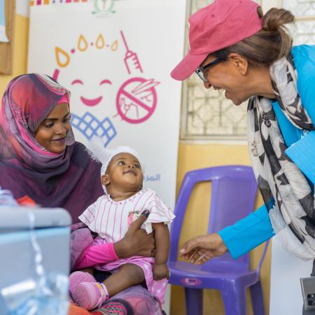 NICEF Sudan’s Chief of Health, shares a light moment with Adan Mohammed, 6 months, before she receives the malaria vaccine. Adan is the very first child to be vaccinated against malaria in Sudan.