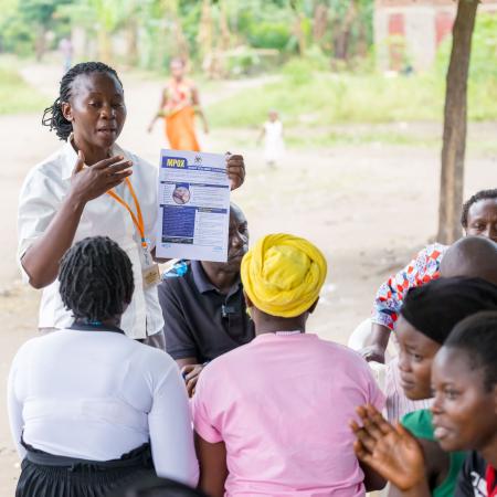 In a community outreach event, Ms. Mbambu Agnes, a Senior Health Educator from Kasese District, educates residents of Kamukumbi Mughongo Village.
