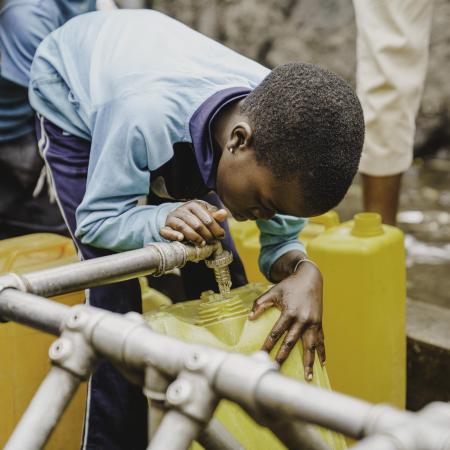 Un enfant remplit un seau d'eau propre en RD Congo.
