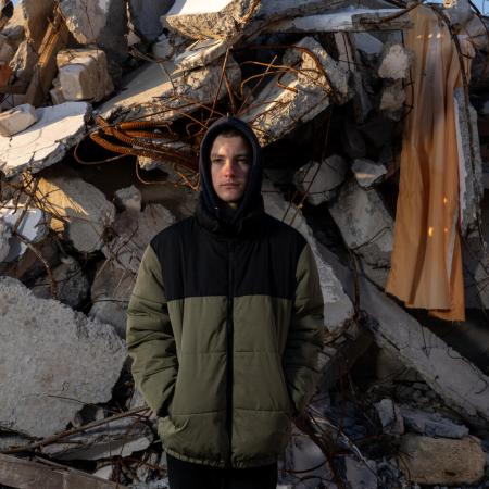 In Ukraine, a boy stands in front of rubble.