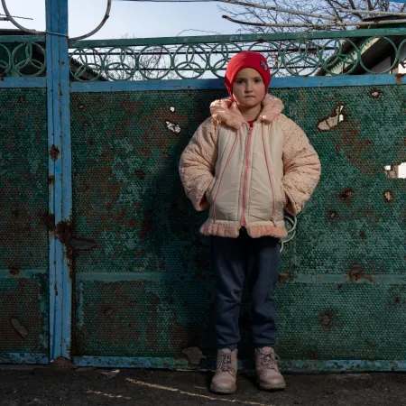 Un enfant ukrainien regarde l’objectif, vêtu d’une veste d’hiver et d’une tuque rouge.