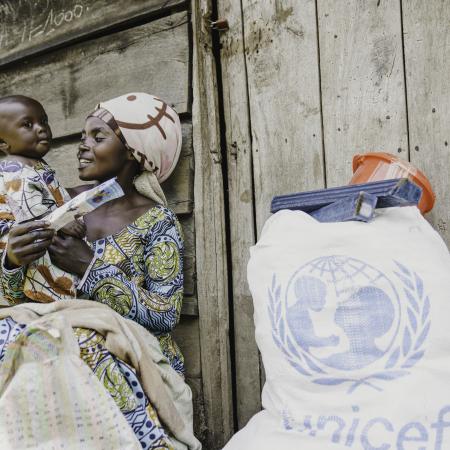Judith, a mother of three, sits in front of her shelter with her child after receiving essential household items at the distribution site in Rugari, Rutshuru territory, North Kivu province, DR Congo, on 27 February 2025.