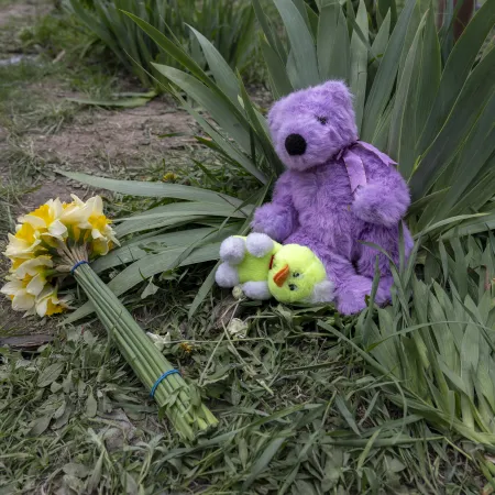 A bouquet of yellow flowers and soft toys lie on the ground near the site of a missile strike, left in memory of the children killed in the early morning attack.
