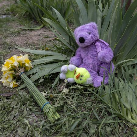 A bouquet of yellow flowers and soft toys lie on the ground near the site of a missile strike, left in memory of the children killed in the early morning attack.