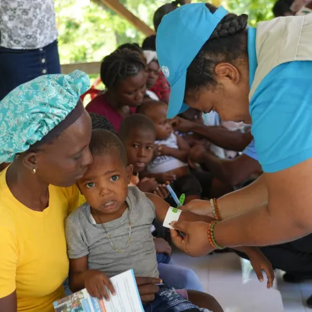 Child sitting on mother's lap getting screened for malnutrition in Haiti at UNICEF-supported mobile clinic