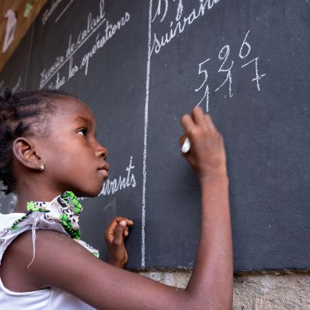 Une fille écrit sur un tableau dans un espace d’apprentissage temporaire (TLS) à Fada N'Gourma, dans la région de l’Est, au Burkina Faso.