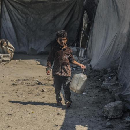 Un garçon transporte un jerrycan d’eau à Gaza.