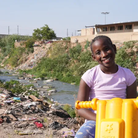 Le 16 septembre 2025 : Ompfuna, dix ans, roule en trottinette le long de la rivière polluée de Jukskei à Johannesburg, en Afrique du Sud.
