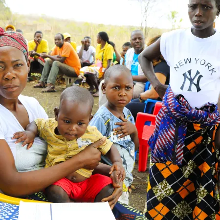 Mother holds her baby at a health centre with others gathered