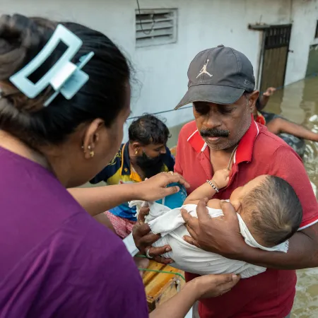 Sri Lankan rescue workers help transport stranded family with baby onto rescue boat