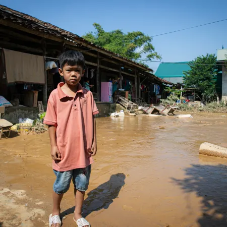 Child stands in flood waters beside his home in Viet Nam