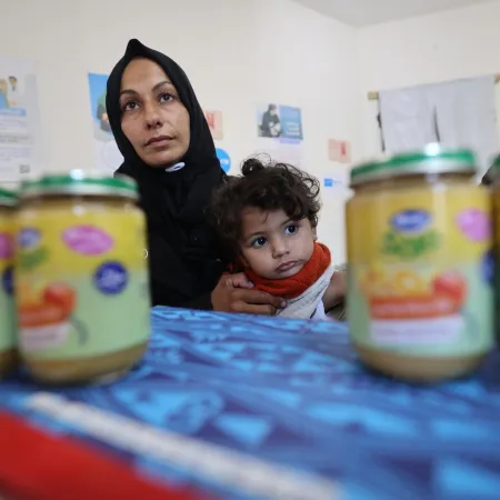 A mother holds a child while waiting to receive ready-to-use-complimentary-food.