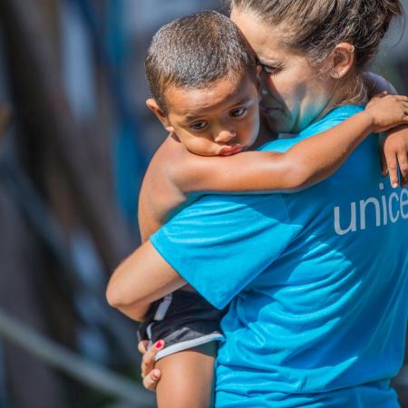 A UNICEF worker holds a toddler.