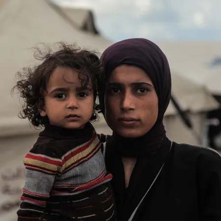 In Gaza city, a mother holds her daughter close as she looks at the camera.