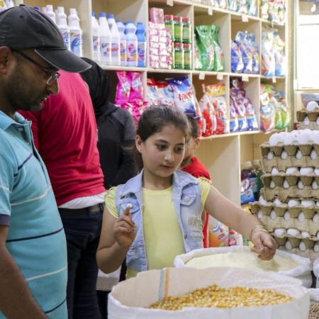 Lamis helps her father shop at a store in Aleppo.