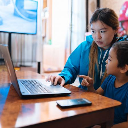 Aizaada, 21, a UNICEF Volunteer, transcribes lessons at home in Osh, Kyrgyzstan with her nephew, Aliyar.