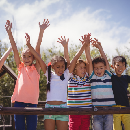 Des enfants souriants, les mains levées en l’air. 